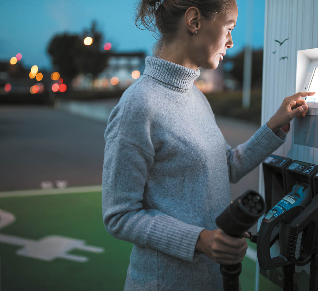 Young woman charging an electric vehicle  Car sharing concept 