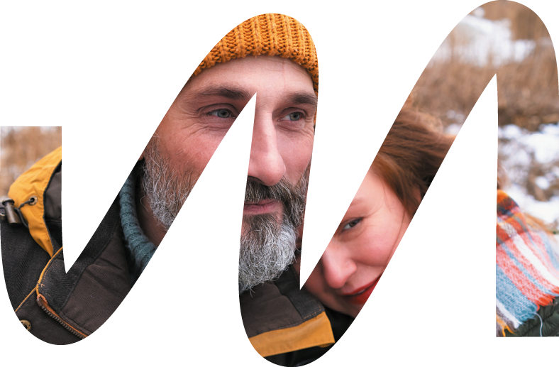 Tender middle aged couple on winter vacation away in wild dressed up warmly  Smiling middle aged man and woman in snowy nature or park together  Family seasonal vacation concept  