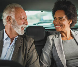 Shot of two successful multi-ethnic business people talk about work while sitting in the backseat of a car during their morning commute 