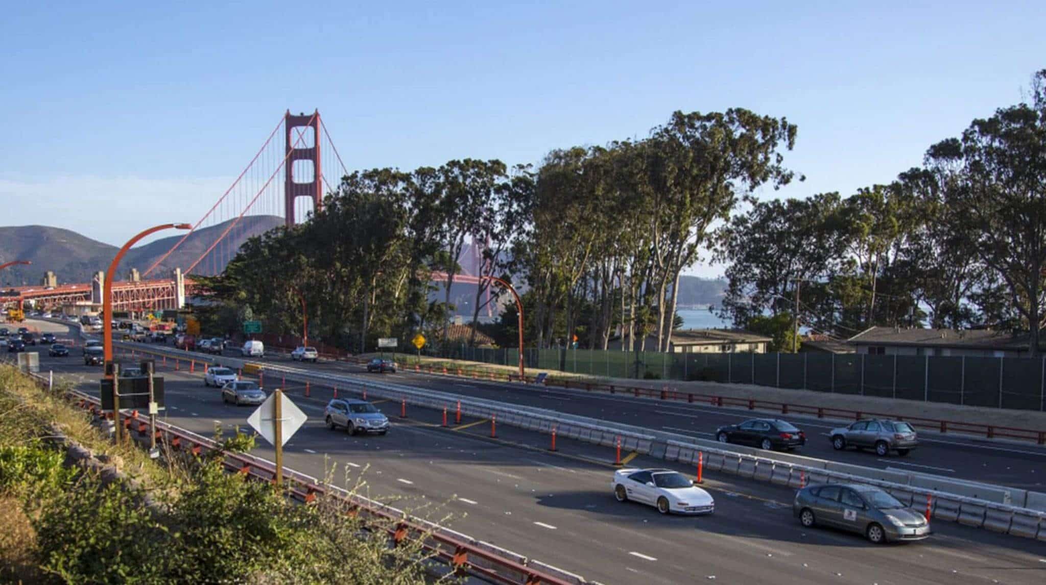 View of Presidio Parkway Road, California, with multiple cars and the Golden Gate Bridge in the distance