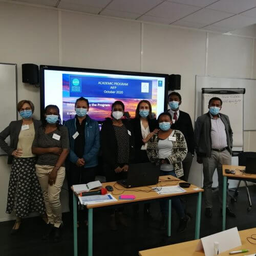 Team standing in front of projector screen with masks on
