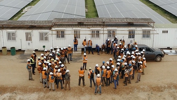 Workers in hard hats standing outside solar plant