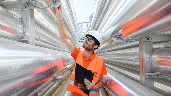 Man in white hard hat and high vis examining steel pipes