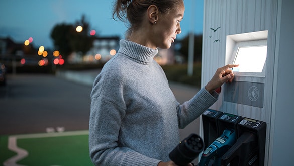 Woman charging her electric vehicle in the evening time