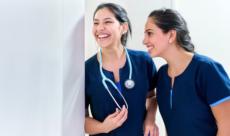 Two nurses in scrubs smiling