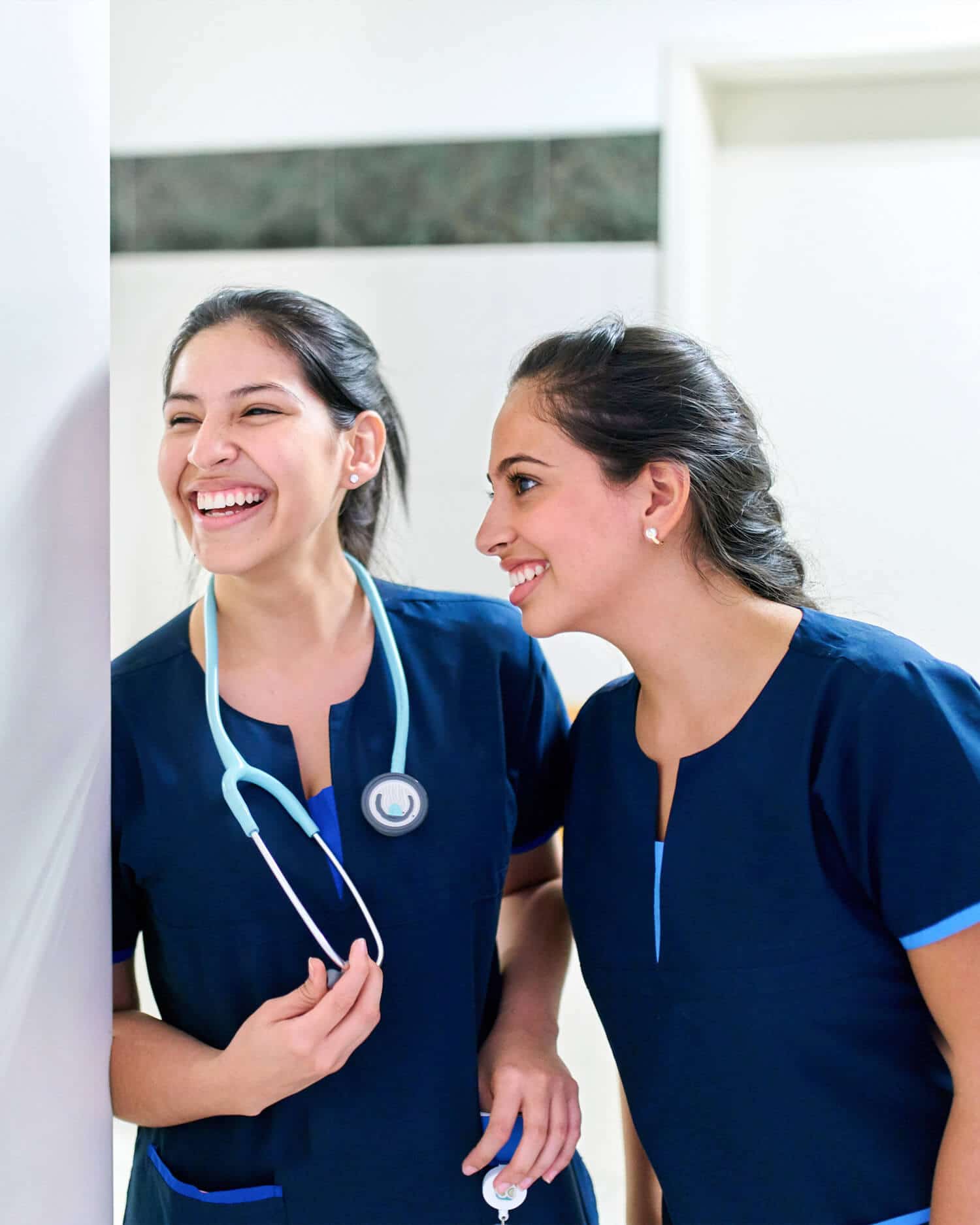 Two nurses in scrubs smiling