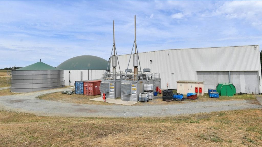 Biogas processing units behind a white hanger