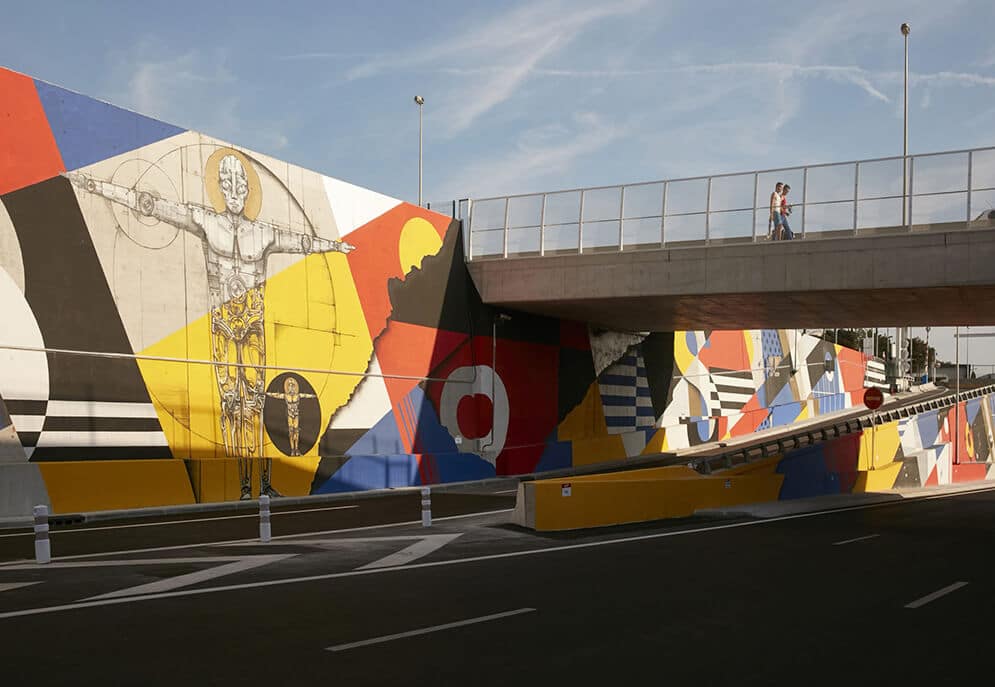 Footbridge over road with colourful imagery on wall