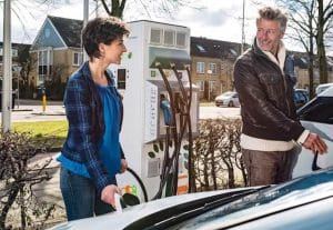 Woman and man stood at an electric vehicle charging point, charging their vehicles