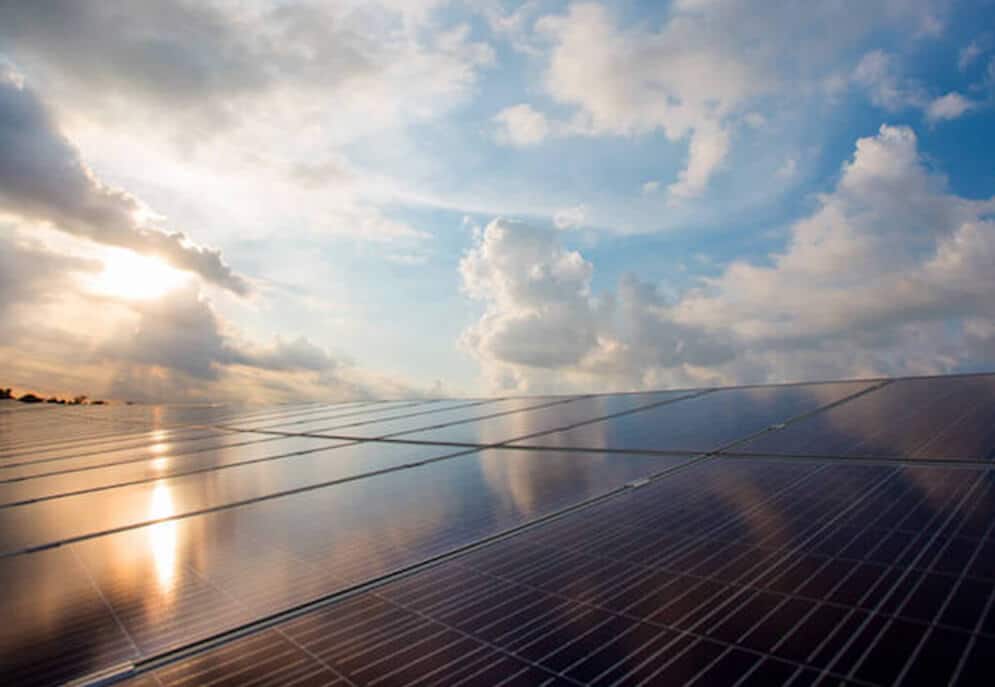 Image of solar panels with a partly cloudy sky reflected in them